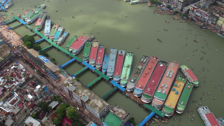 Large colorful ships docked on a pale green river running through a city