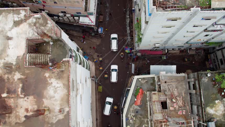 Three white vehicles drive down the small city road