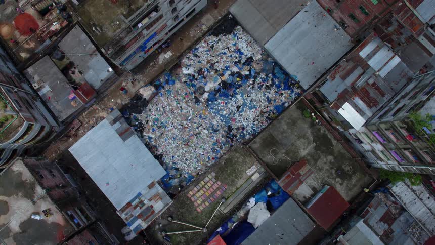 People move through a trash dump in located in the densely packed but rundown section of a city