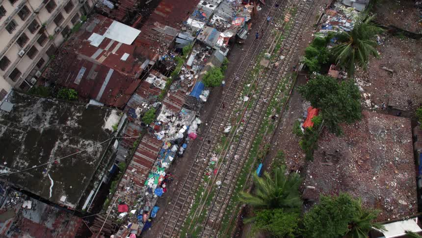 People walking on train tracks next to houses and trees
