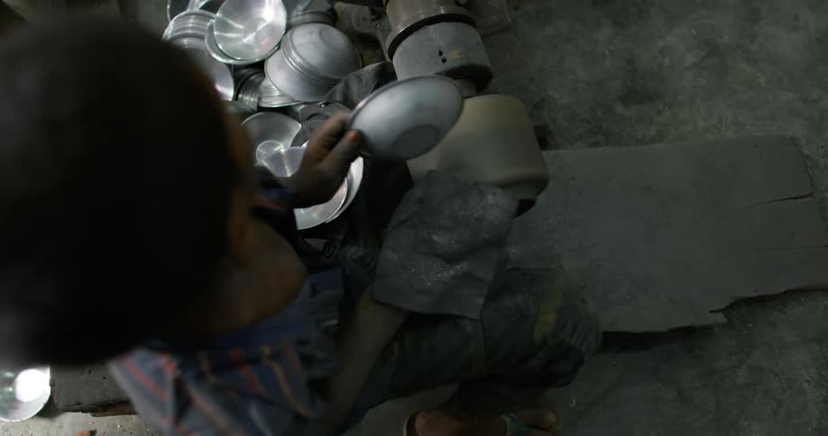 A young boy making bowls in a factory