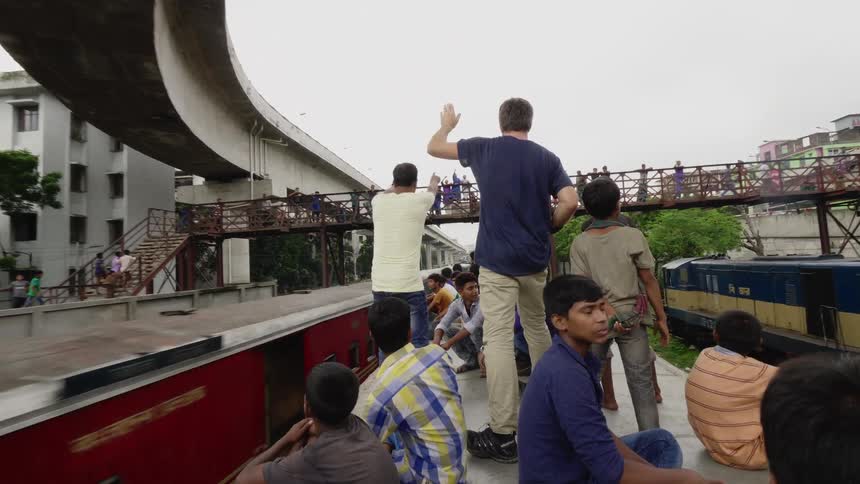 Photographer joins boys and teenagers riding on the roof of a moving train