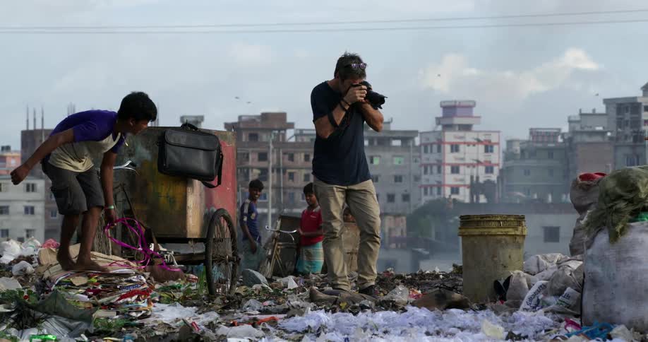 A man is photographing people clearing garbage by the city