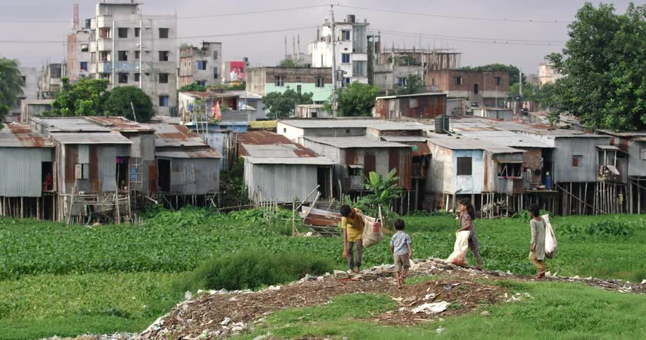 Children pick up trash in a field near their homes in a developing city