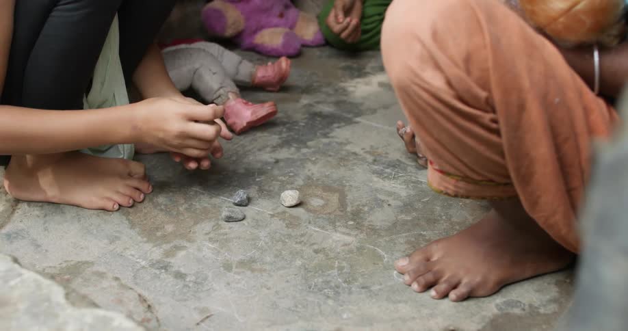 A person tossing and catching rocks on the ground