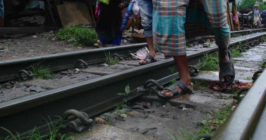 People walking on train tracks with trees and the sky in the background