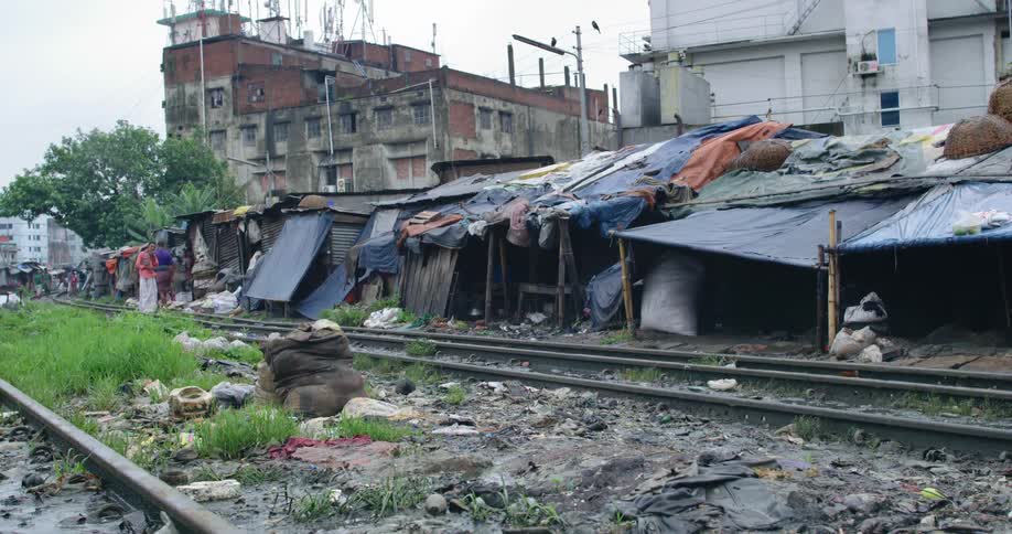 People in a primitive area standing in front of shacks