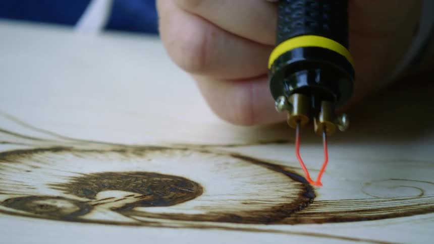 A man burns a picture on to wood