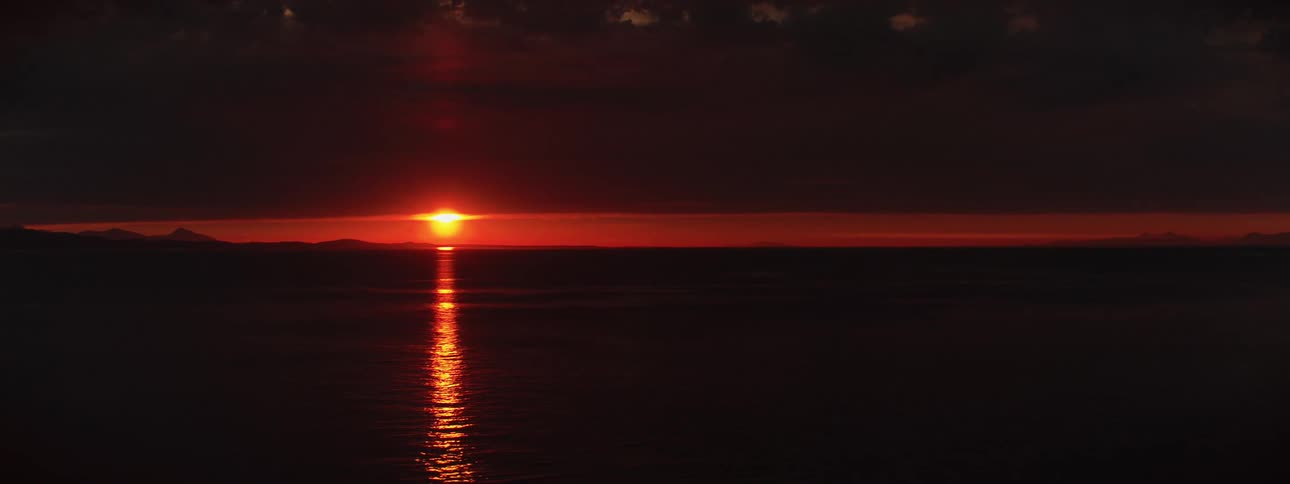 The sun setting over a lake in an orange sky