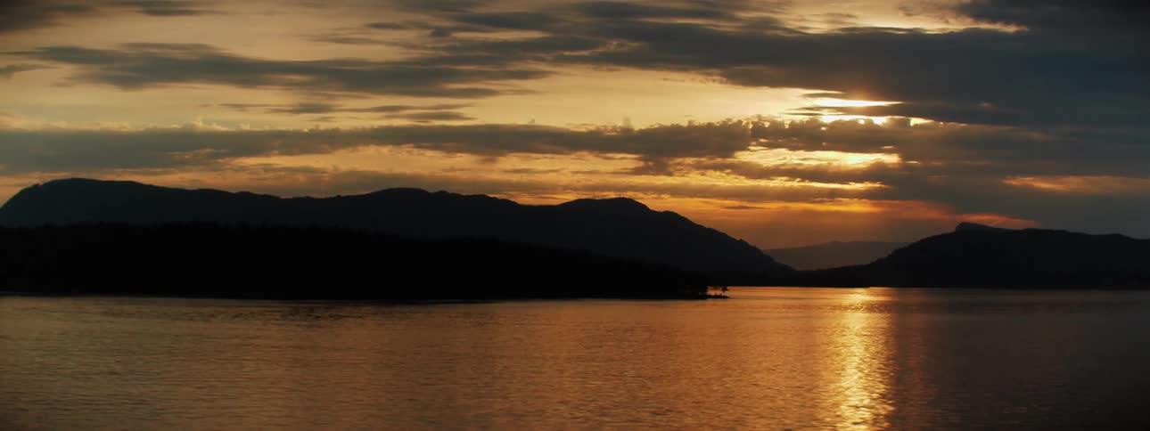 The sun setting over hills on the coast