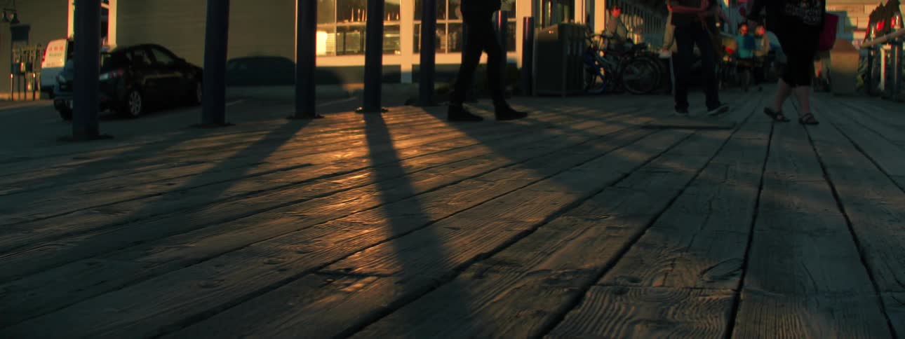 People walk across wooden boardwalk toward rail