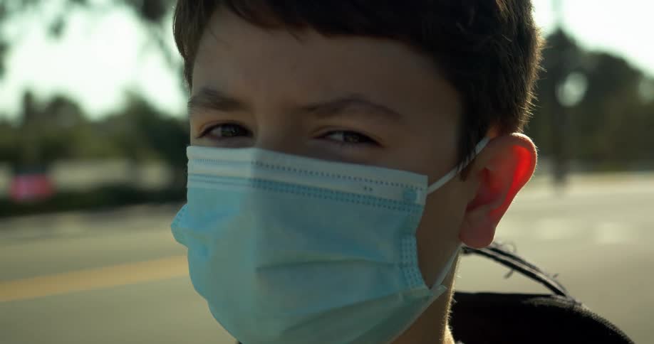 Boy with a blue mask stands in the street