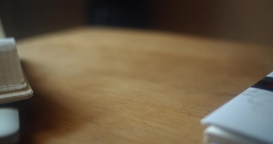 The hand of a man as he picks up his glasses and a book