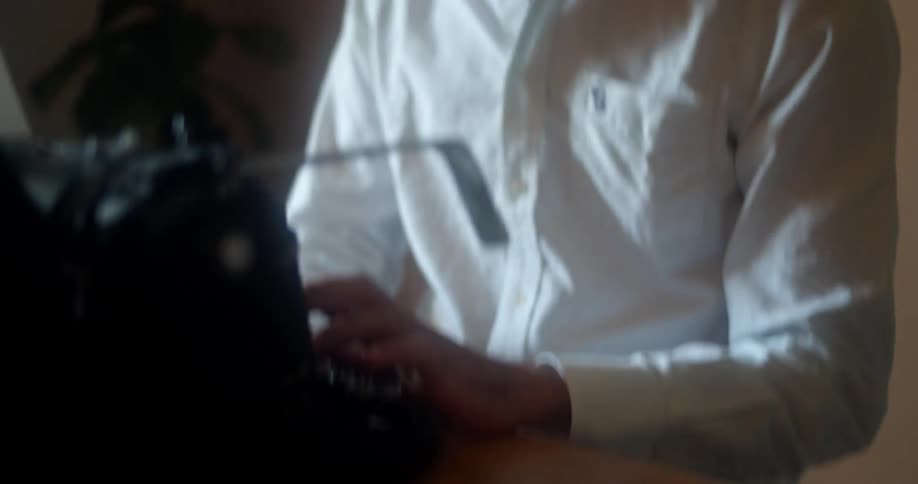 A man in an office types on a vintage typewriter