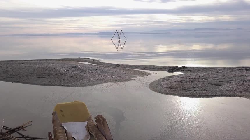 Aerial view of debris on the sand shore of a lake at sunset