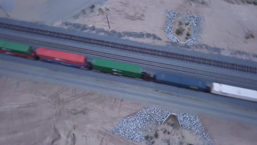 Spinning aerial view of the colorful wagons of a freight train moving on tracks