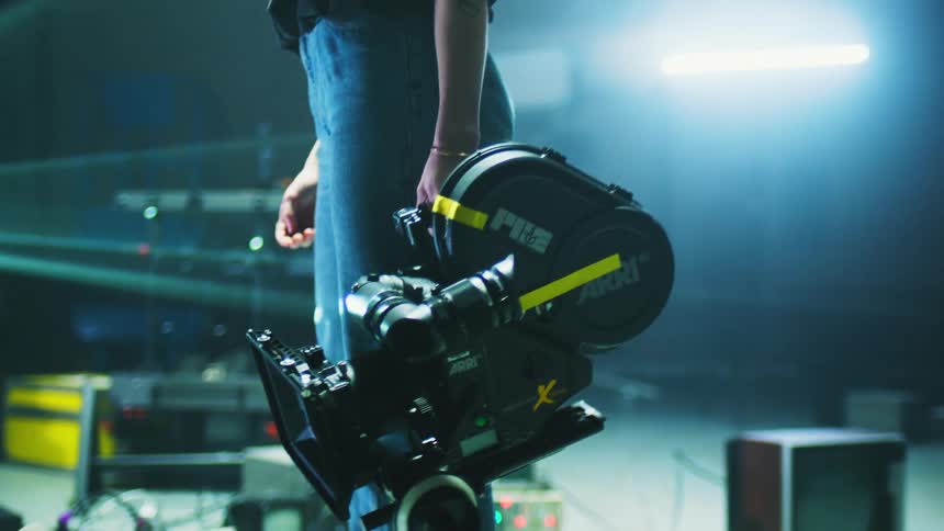 A woman on a set holds a film camera