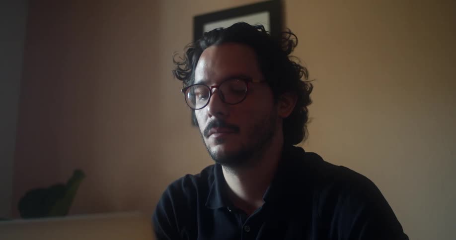 A man at home talks with someone while using his laptop