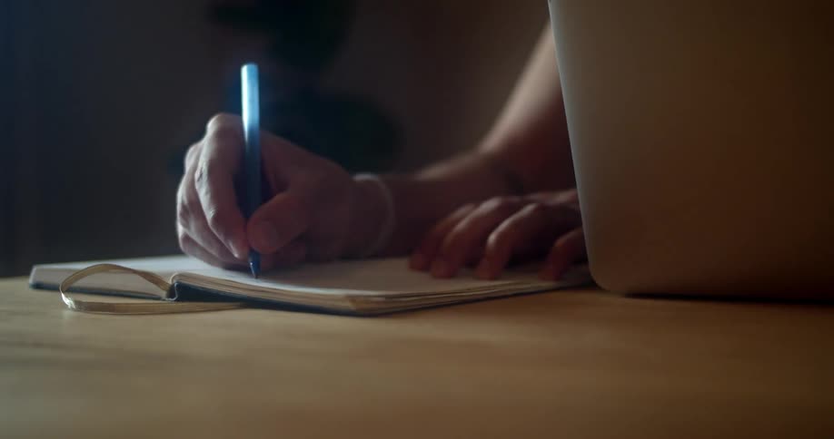 A person is writing in a journal indoors