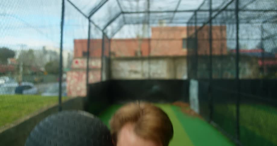 A man with an exercise ball exercising with buildings the sky and clouds in the background