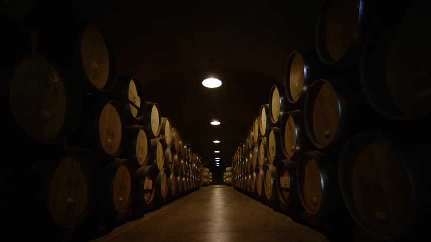 Wooden barrels piled up on a dimly lit warehouse