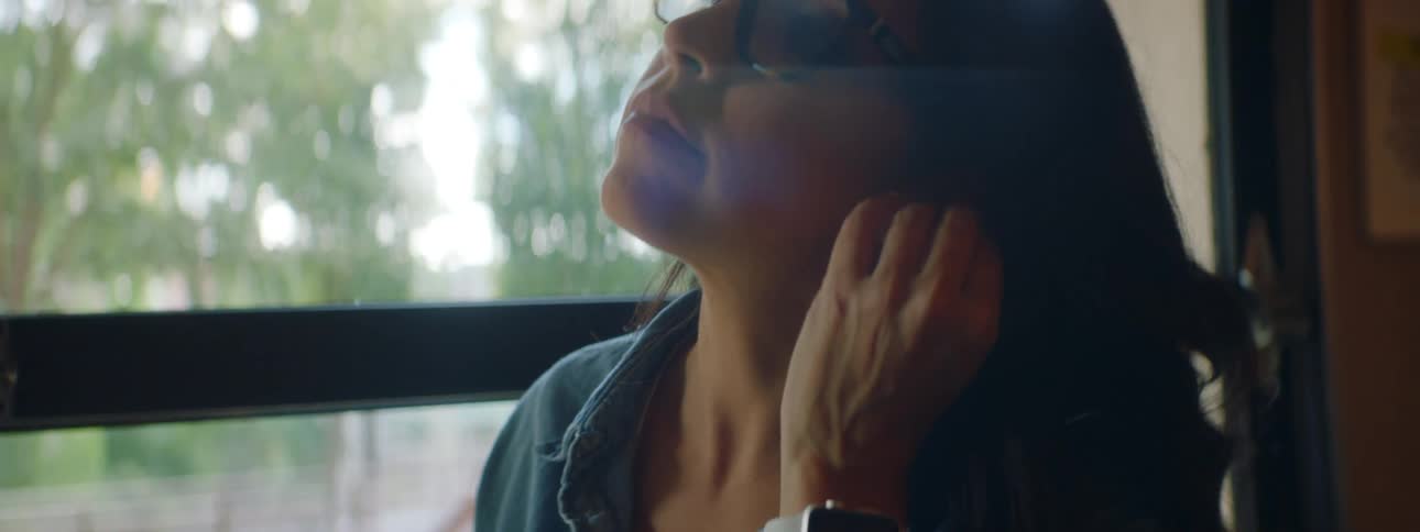 Woman sitting in a table at a restaurant puts earbuds and checks her smartphone