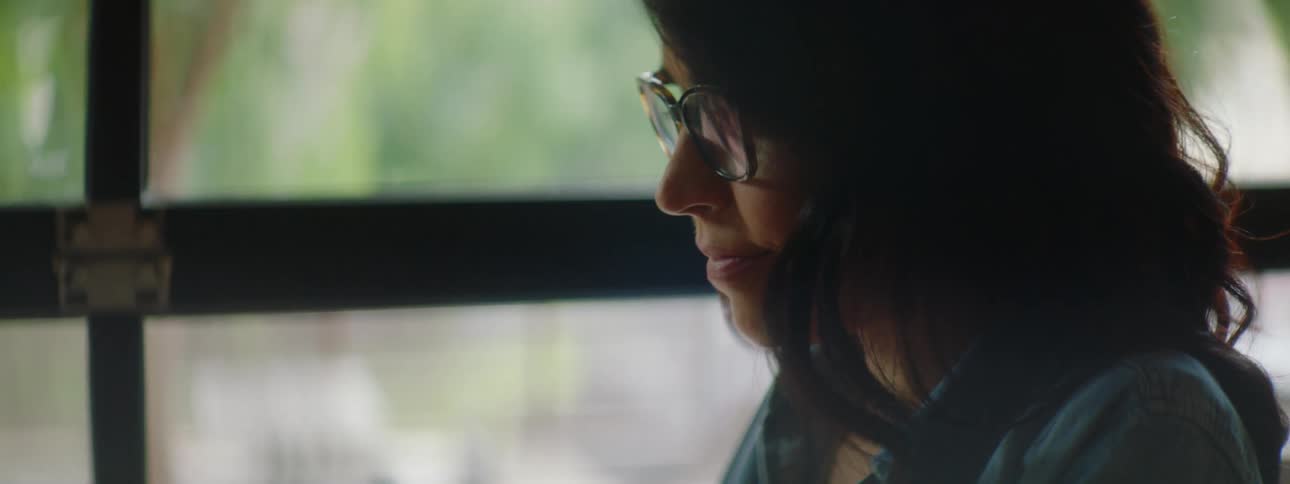 A woman sits at a table and types on a laptop