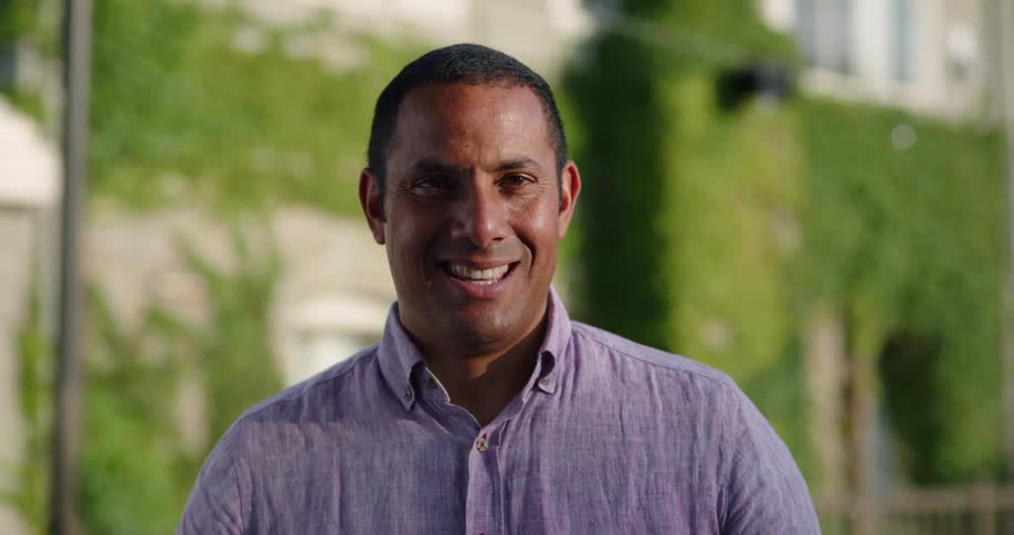Middle aged man standing outdoors smiles at the camera