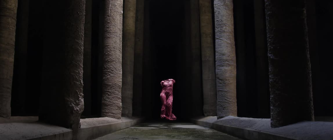 A statue sits between the dark pillars