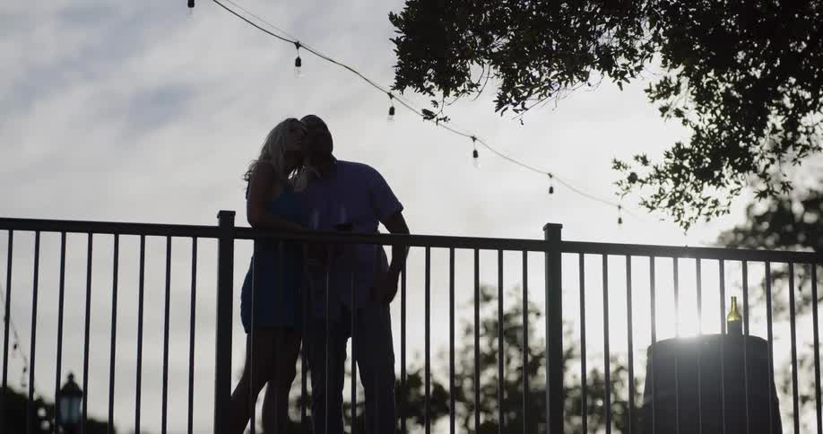 A man and woman drink wine and talk while looking at the scenery outdoors during the day