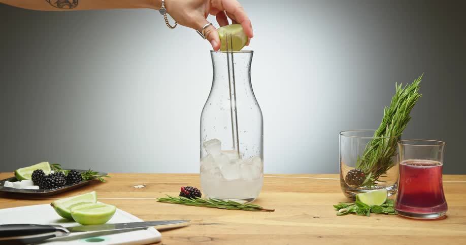 A woman squeezes a lime in to a carafe with ice
