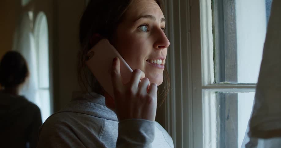 Woman smiling and laughing on phone call while looking out window