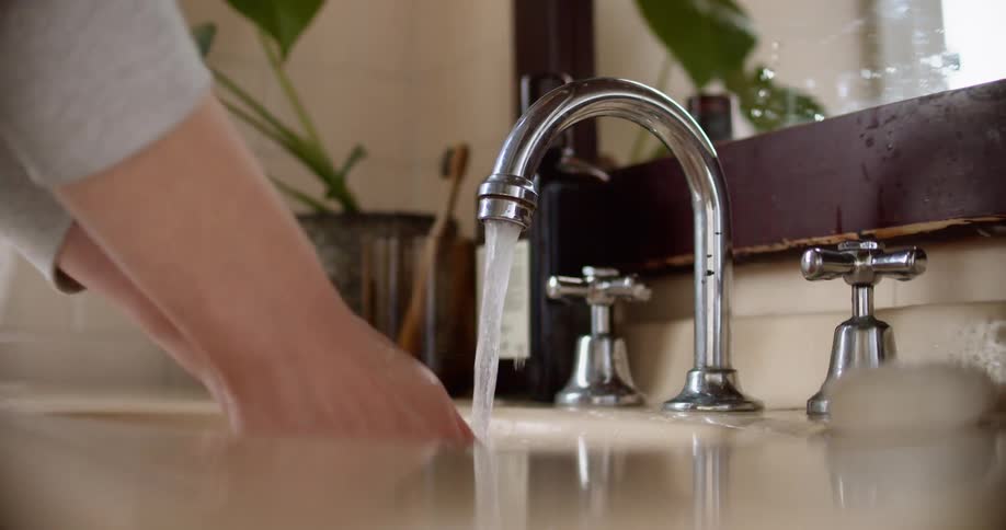 A person washing their hands with bar soap at a bathroom sink