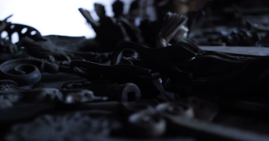 Rusted nuts and bolts and tools sit on a dark wooden table in a room