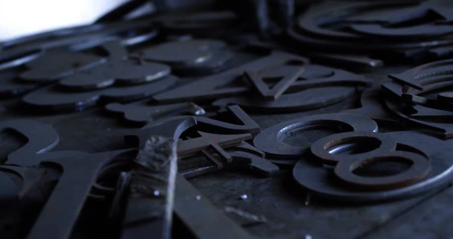 The table is full of metal letters and numbers for signs
