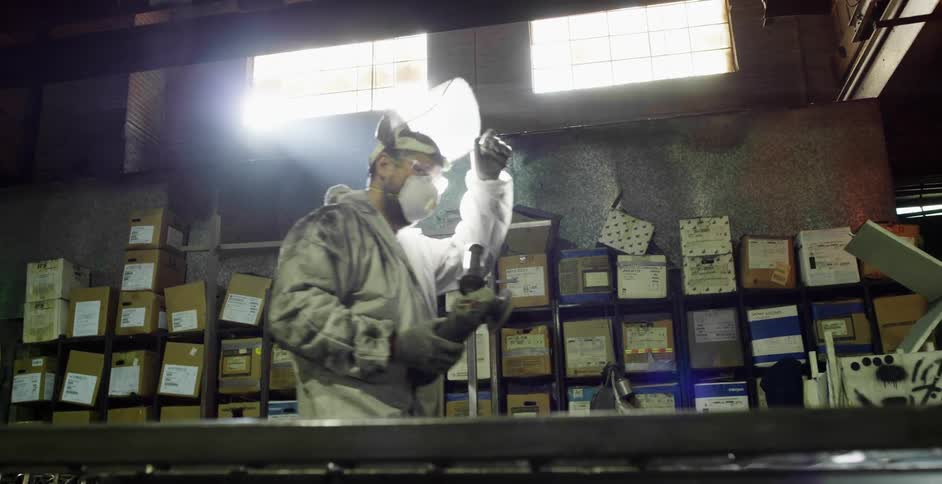 A man carries his angle grinder in the warehouse