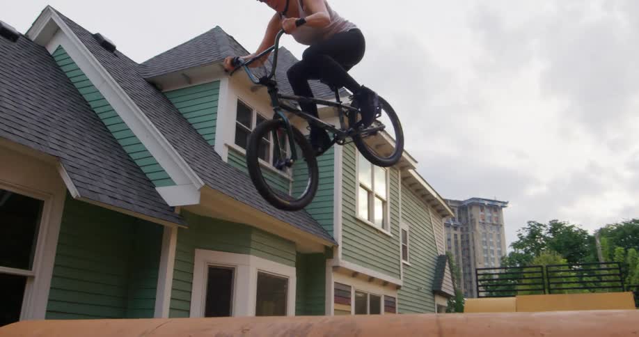 A girl on a bike jumps as she rides over a ramp in her back yard