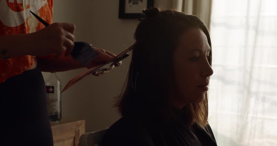 A woman sits in a chair as another woman uses a brush and foil to color her hair