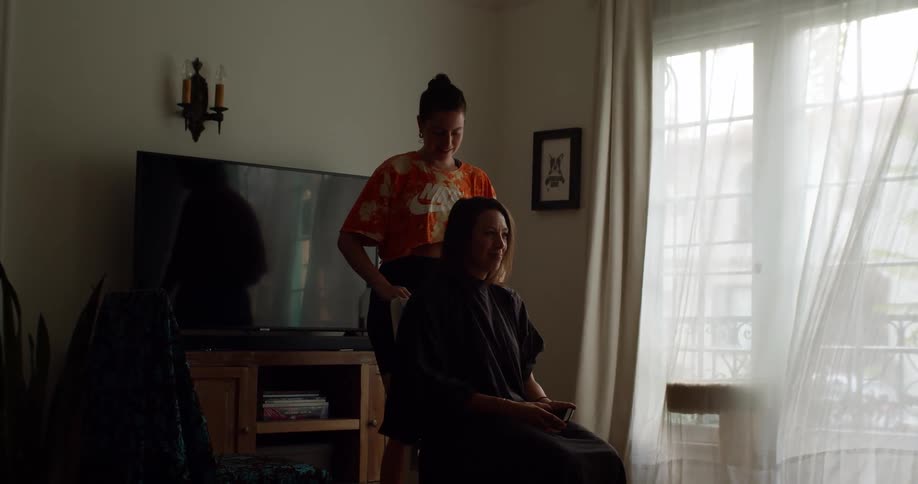 A woman combs another womans hair before cutting it