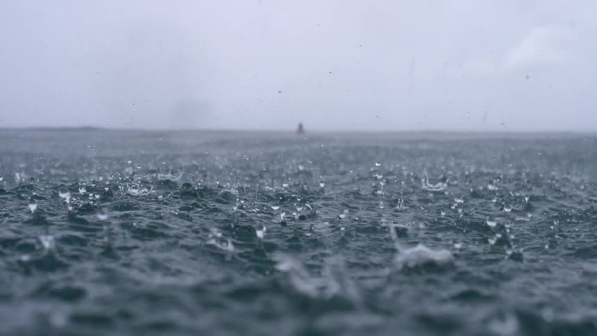 Raindrops falling on ocean water during a rainstorm