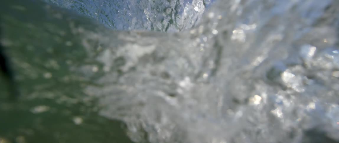 A large ocean wave rolling towards a beach engulfs the camera