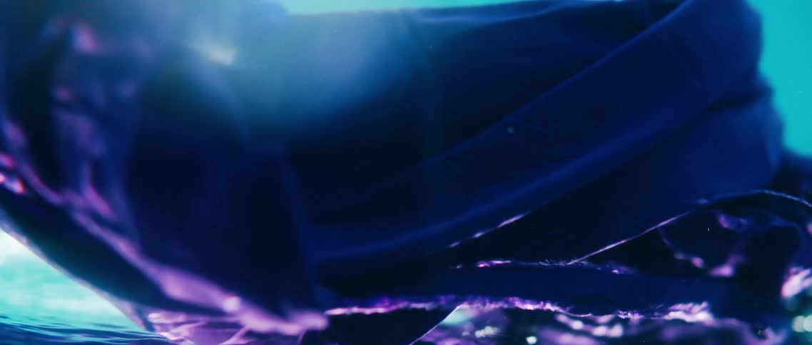 A purple cloth underwater with bubbles and light