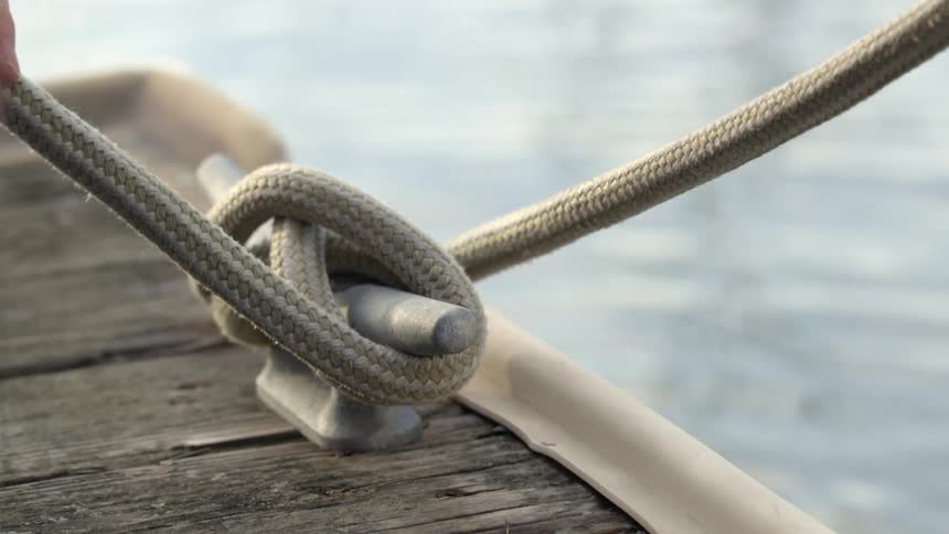 A person ties a mooring line to a pier during the day
