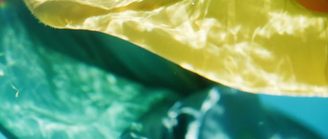 Green and yellow fabric float underwater in a pool