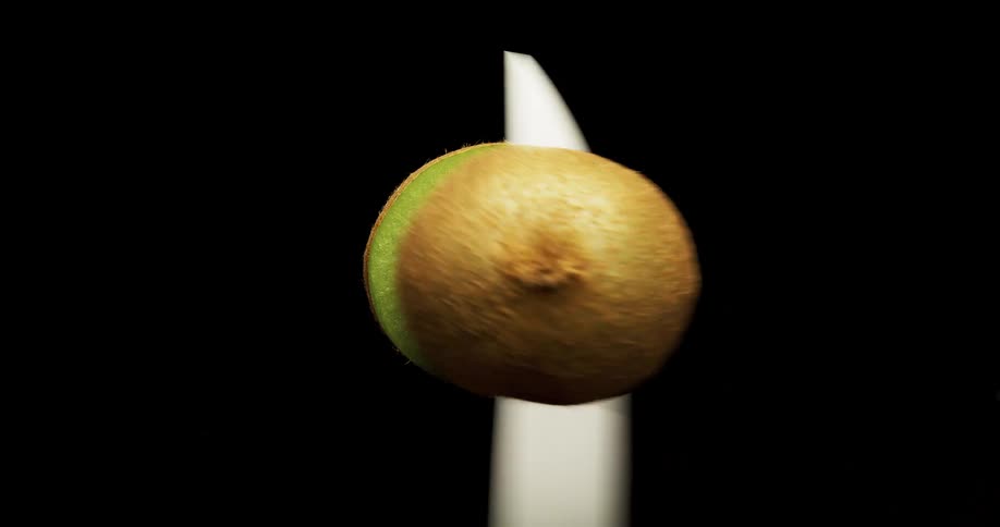 A knife cuts a kiwi fruit in half