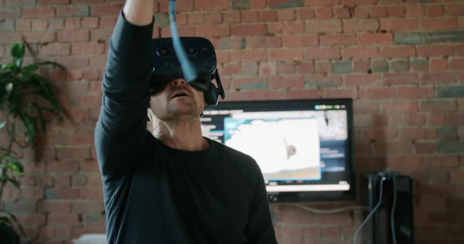 A male with virtual reality gaming gear on playing a video game