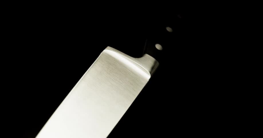 A kitchen knife spins in the air in a dark room