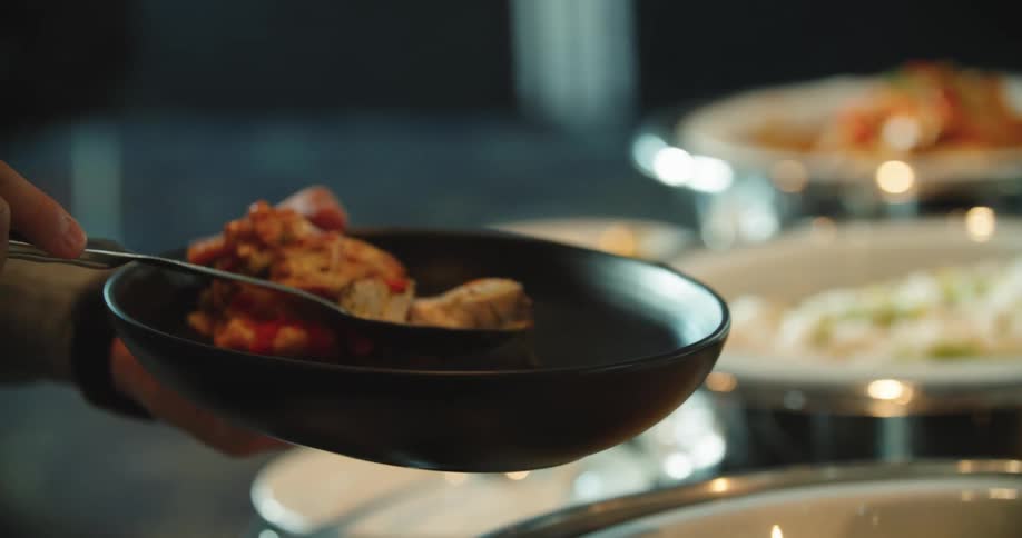 Person serves themselves from large bowl sitting on buffet table