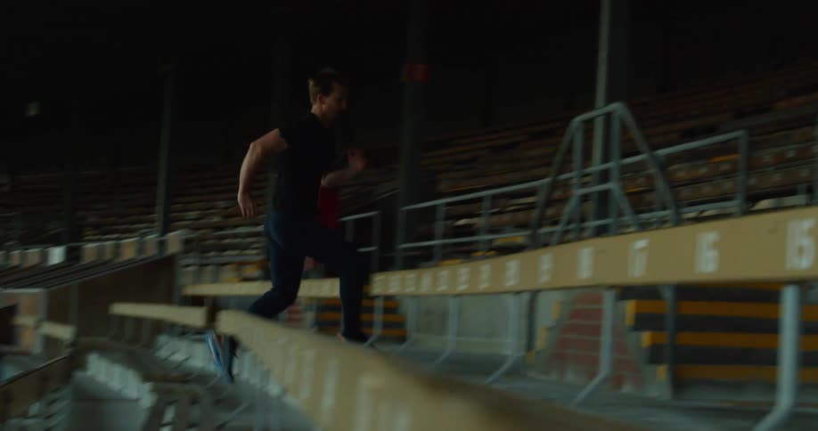 Man runs up bleachers in empty stadium