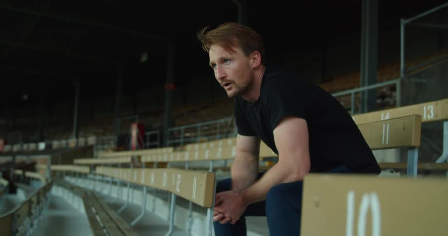 Man sits on bleachers in empty stadium to catch his breath